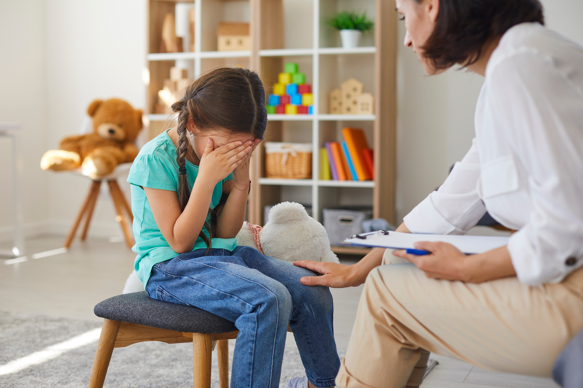 Small Girl Sitting, Covering Face with Hands and Crying during Visit to Child Psycologist
